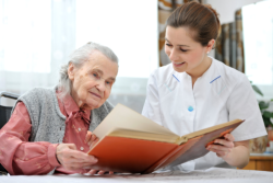 Old woman with her caregiver reading a book